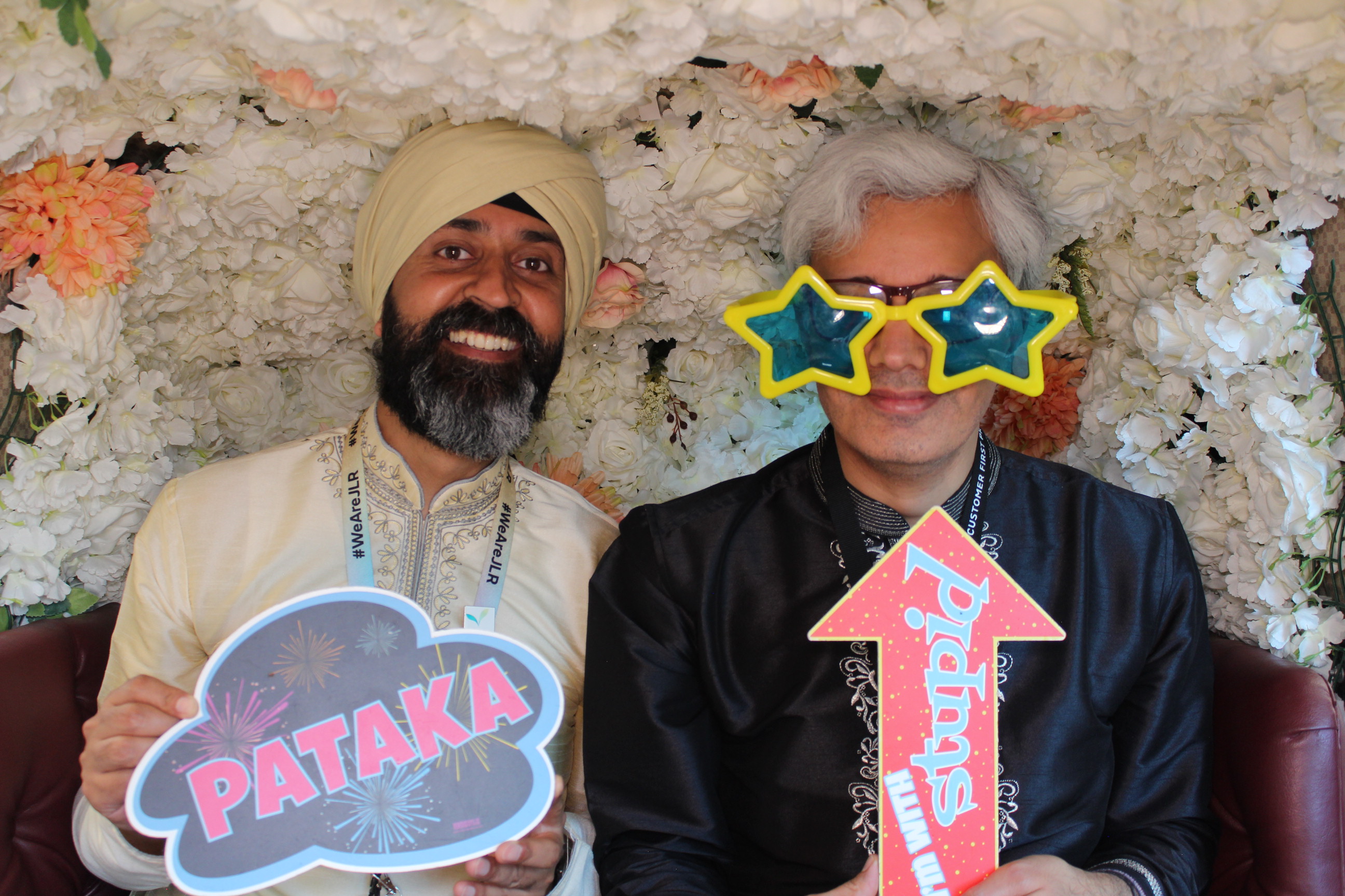 Group of friends wearing party hats inside a decorated tuk tuk photobooth at an event